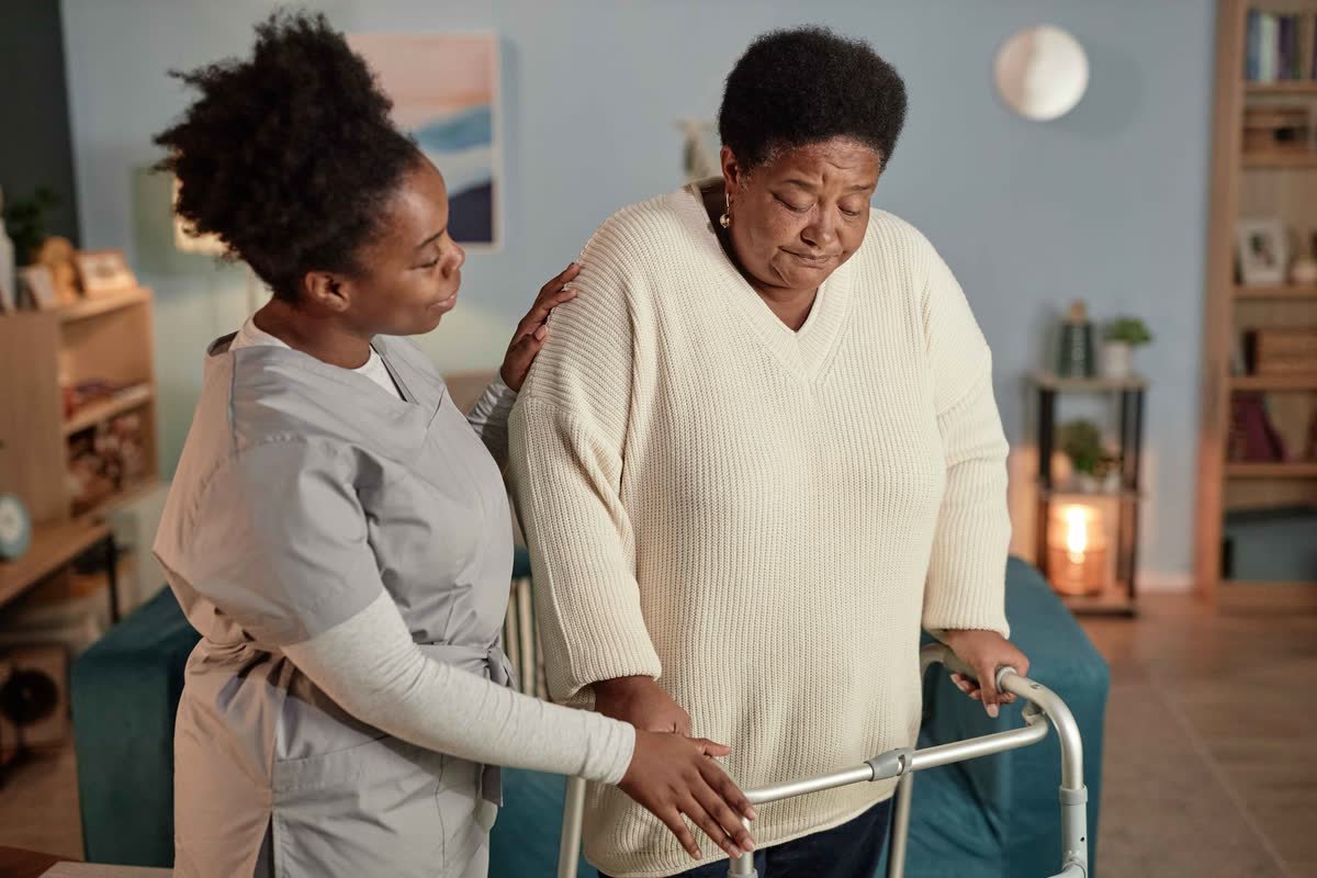 A carer gently supporting a senior woman as she walks